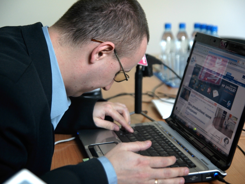 Słabowidzący mężczyzna przegląda strony internetowe na laptopie