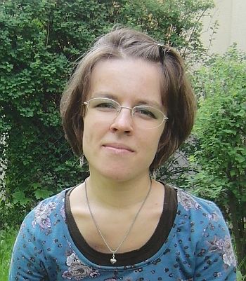 Joanna Krzysztofik stoi na tle ogrodu