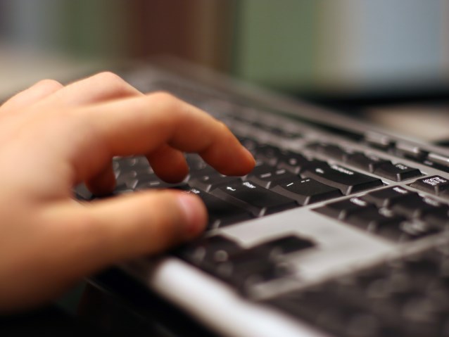 dłoń pisząca po klawaturze laptopa