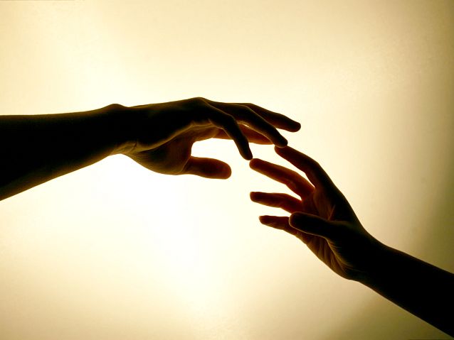 Dwie ledwo dotykające się palcami dłonie dwóch osób