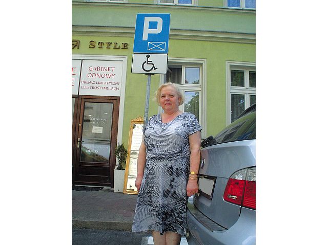 Teresa Rękosiewicz stoi przed znakiem drogowym oznaczającym kopertę