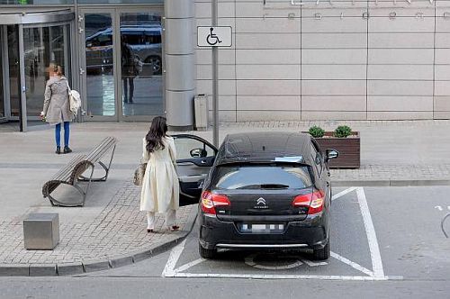 Szykowna młoda kobieta wysiada z zaparkowanego na 