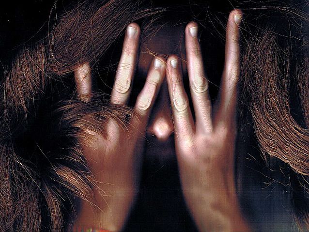 Przerażona kobieta chowa twarz w dłoniach
