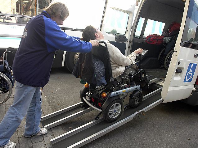 Osoba na wózku wjeżdża do busa z pomocą kierowcy