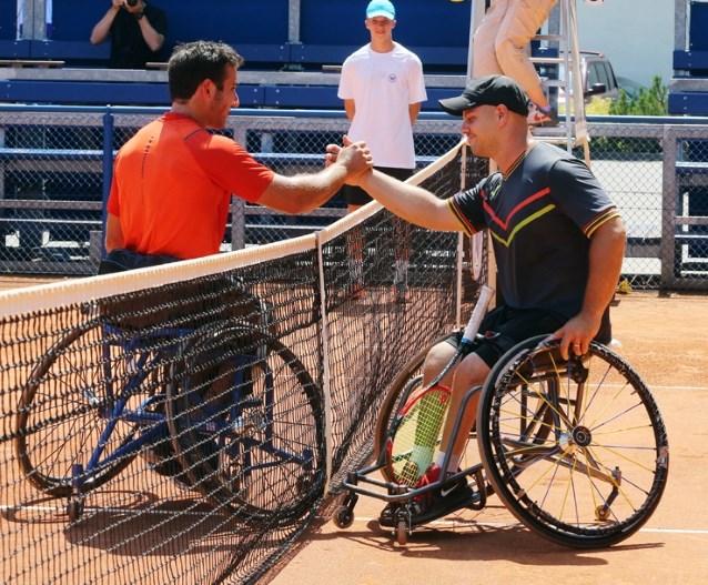 dwóch mężczyzn na wózkach, tenisistów podaje sobie dłonie nad siatką