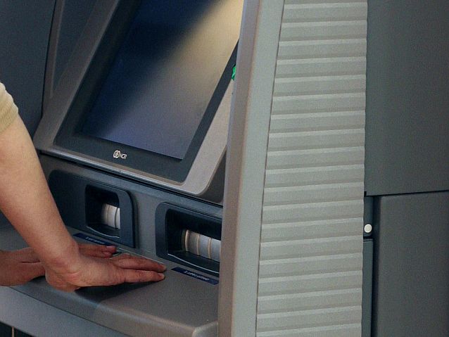 Ręce położone na bankomacie
