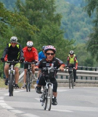 Andrzej Łukasik jedzie na rowerze w stroju kolarskim, za nim inni mężczyźni na rowerach