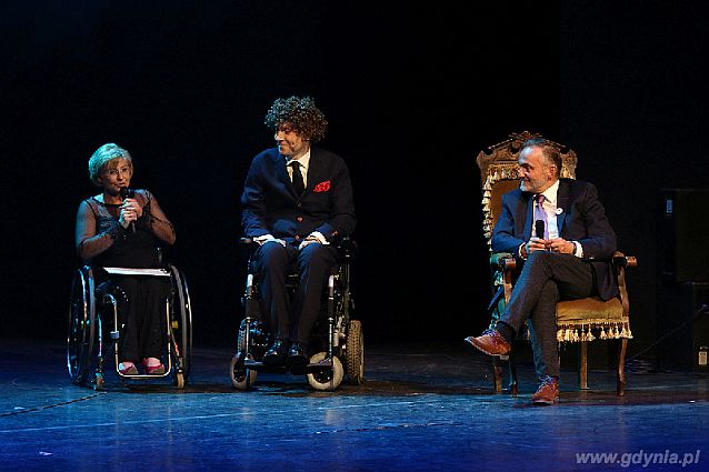Prowadzący galę na scenie: poruszający się na wózkach Beata Wachowiak-Zwara i Piotr Pawłowski oraz siedzący obok w fotelu Wojciech Szczurek