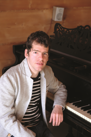 Grzegorz Płonka opiera się łokciem o fortepian