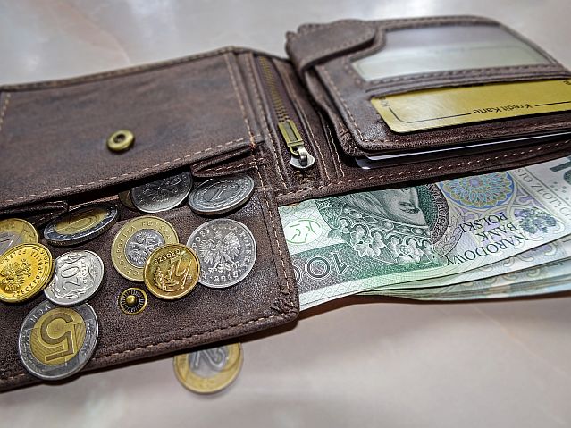 Leżący portfel z wysypującymi sie monetami i wystającymi banknotami