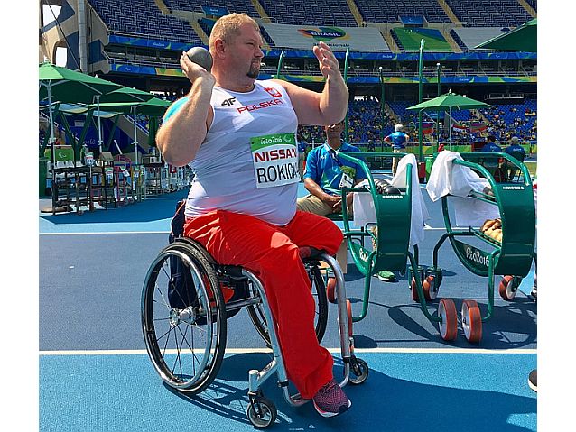 Janusz Rokicki siedzi na wózku z kulą lekkoatletyczną w ręku