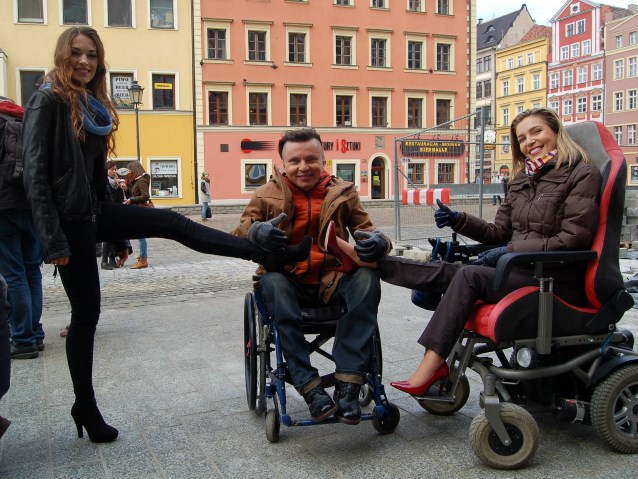 od lewej: kobieta w szpilkach, opierająca nogę o kolano Bartłomieja Skrzyńskiego, obok Agata Roczniak, modelka
