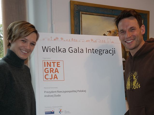 Paulina Chylewska i Tomasz Wolny stoją przy tablicy z napisem wielka Gala Integracji