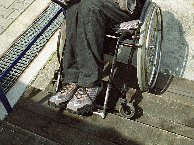 Człowiek na wózku inwalidzkim na drewnianych schodach