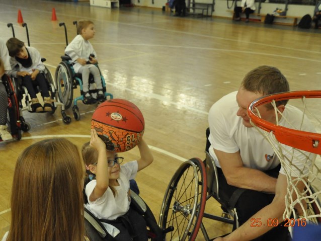 wolontariusze grają z dziećmi na wózkach w koszykówkę