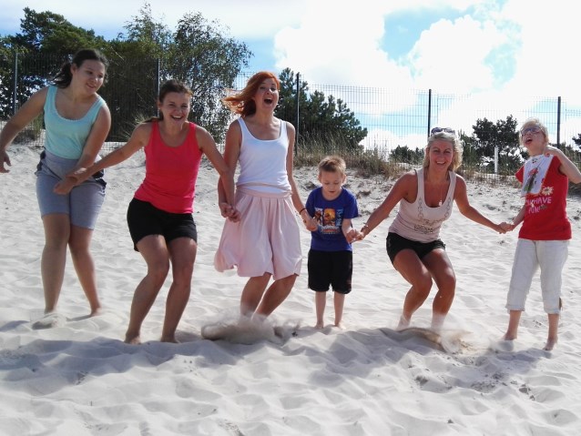 wolontariusze i dzieci razem skaczą na piasku