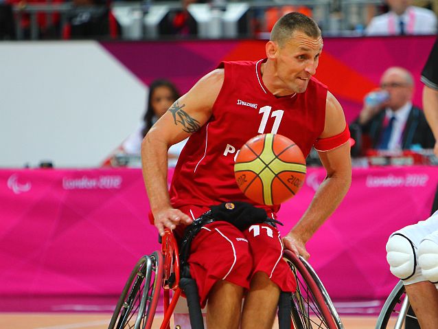 Koszykówka na wózku. Polski zawodnik jedzie z piłką na kolanach