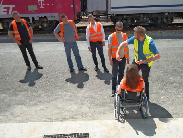 Jeden z trenerów Integracji tłumaczy pracownikom PKP Intercity jak należy podnieść osobę z wózkiem i w razie konieczności pomóc jej przejść jeden schodek na dworcu