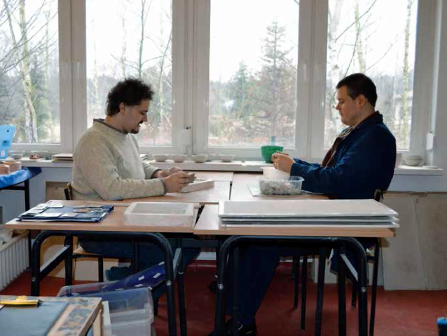 dwóch mężczyzn z autyzmem siedzi przy oknie i pracuje