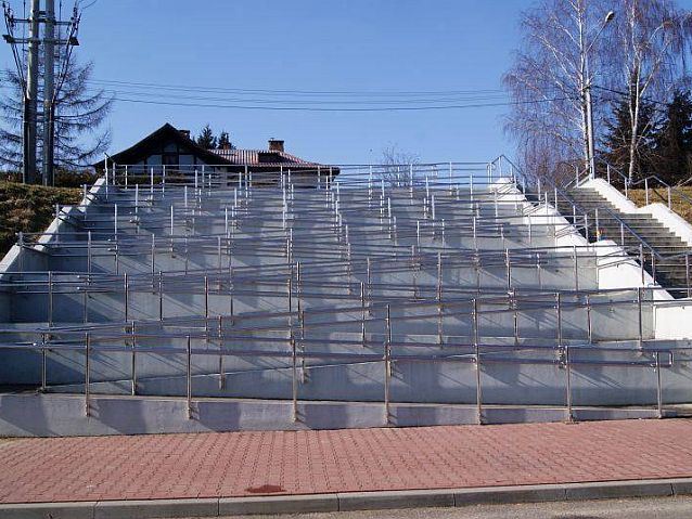 Ogromny podjazd dla osób na wózkach, który składa się z kilkunastu ciągów z barierkami