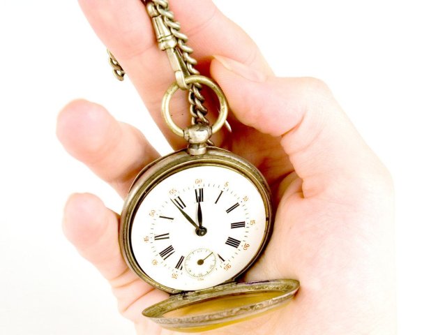 kobieca dłoń trzyma zegarek kieszonkowy, wskazujący godzinę 11:50