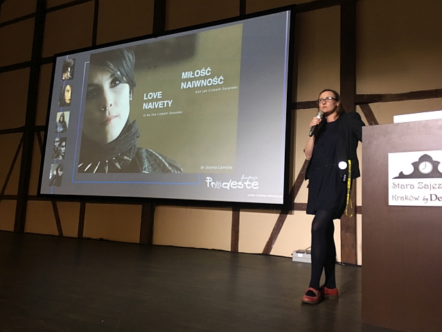 Dr Joanna Ławicka przemawia do mikrofonu na scenie, obok wyświetlona twarz bohaterki Trylogii Millennium