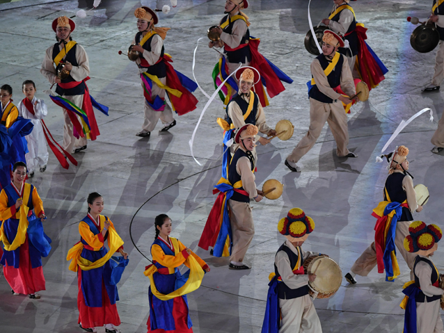 Taniec Koreańczyków ubranych w tradycyjne stroje, grających na bębnach