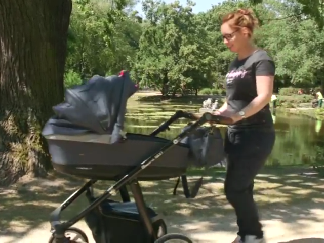 młoda kobieta prowadzi wózek z niemowlęciem. Uśmiecha się do niego