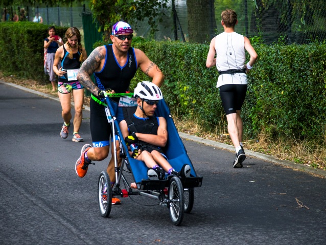 mężczyzna biegnie popychając wózek z synem
