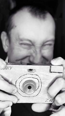 Mirosław Szymański udaje, że robi zdjęcie drewnianym aparatem zdjęcie
