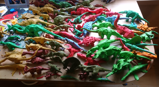 cały stół zatawiony kolorowymi dinozaurami z plasteliny