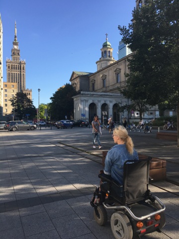 kobieta na wózku elektrycznym porusza się w kierunku Pałacu Kultury i Nauki