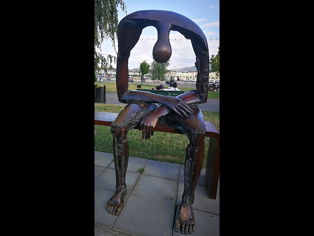 Rzeźba w parku przedstawiająca siedzącego zrezygnowanego mężczyznę, którego korpus to wielka dziura