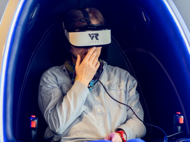 mężczyzna w opasce na oczach VR w specjalnym fotelu