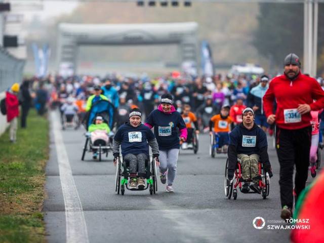 kilkadziesiąt osób pełnosprawnych i z niepełnosprawnością biegnie po asfalcie