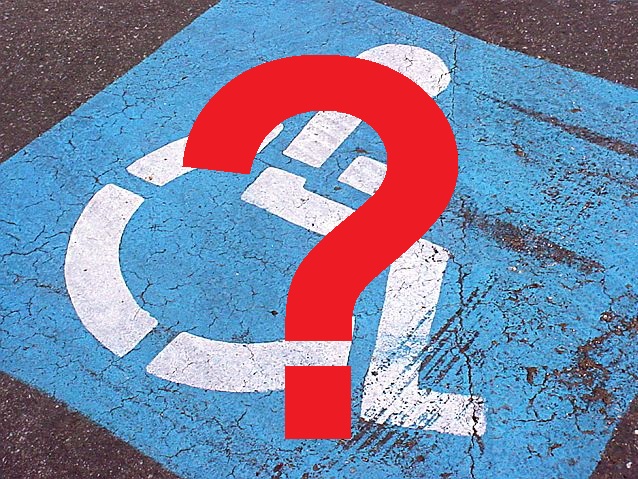 Namalowany na jezdni symbol osoby na wózku na niebieskim tle. Zdjęcie przykrywa znak zapytania