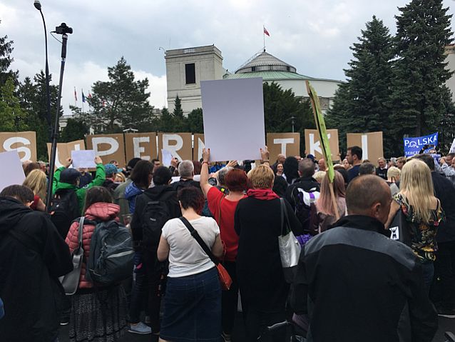 Tłum osób pod Sejmem, ponad głowami widać napis Supermatki
