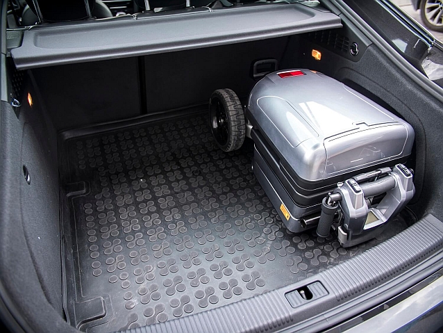 Złożony skuter inwalidzki o wielkości walizki leży w bagażniku samochodowym. Zajmuje niecałą jego połowę