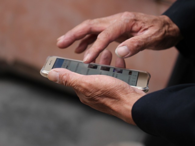 męskie ręce starszej osoby trzymają w ręku telefon komórkowy coś na nim wciskając