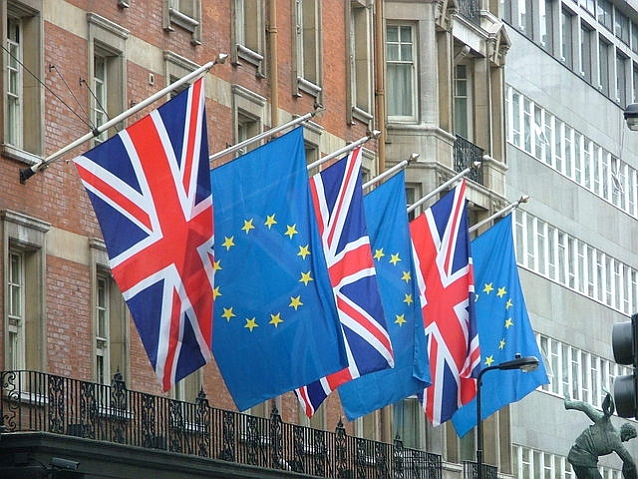 Wiszące na budynku naprzemiennie flagi Unii Europejskiej i Wielkiej Brytanii