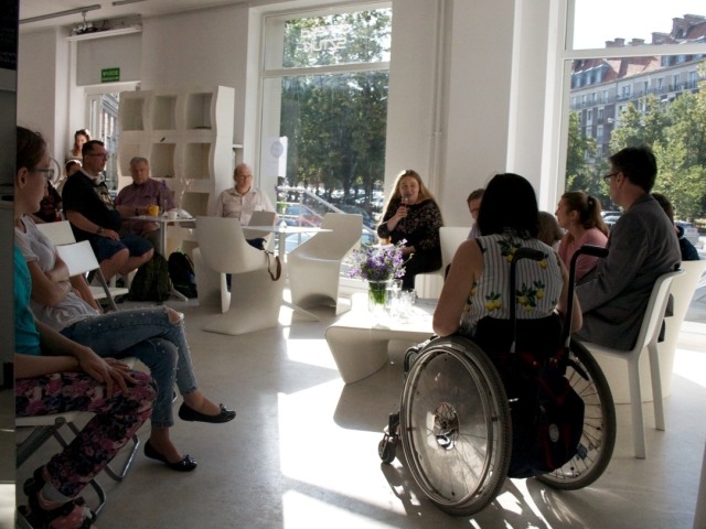 w kręgu siedzą osoby sprawne i z niepełnosprawnością, rozmawiają.