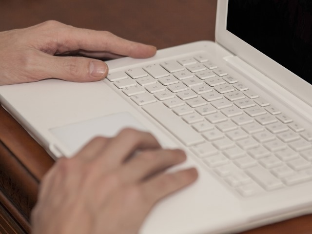 biały laptop na klawiaturze męskie ręce