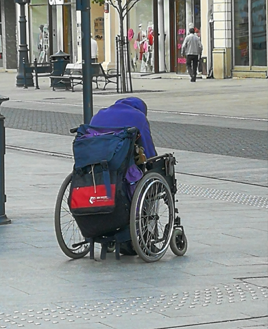 zgarbiony, bezdomny mężczyzna na wózku inwalidzkim