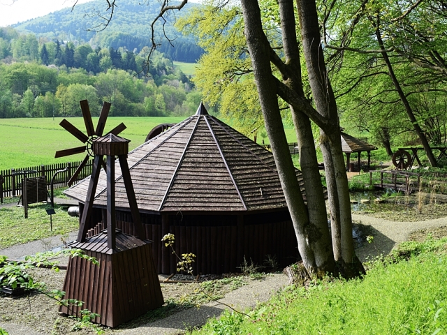 prosta, okrągła, drewniana chata na środku zdjęcia wśród zieleni. 