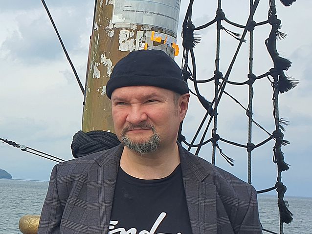 Stanisław Kmiecik stoi na statku na tle masztu