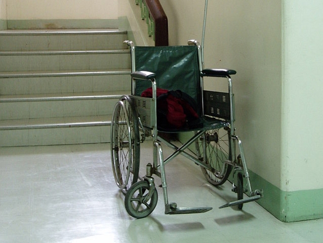Stojący przed schodami stary wózek inwalidzki