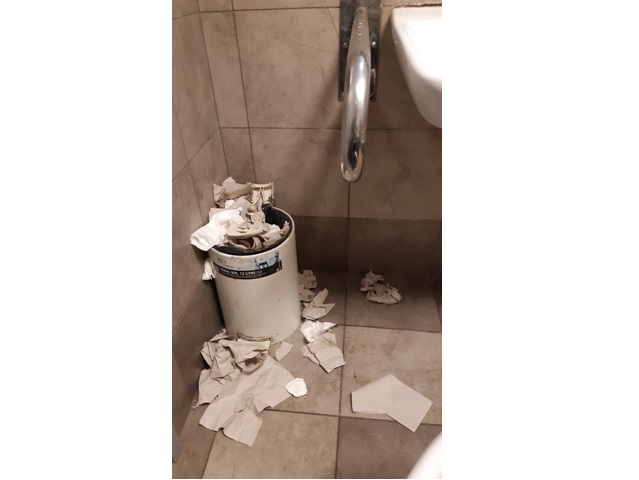 kosz w łazience z którego wywala się papier, leży też naokoło kosza na podłodze