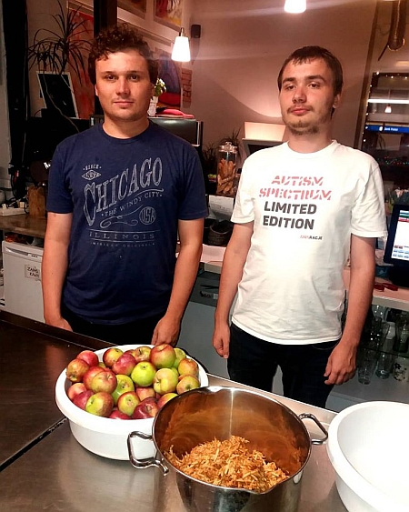 Dwóch młodych mężczyzn stoi w kuchni, przed nimi leżą jabłka i przecier z jabłek