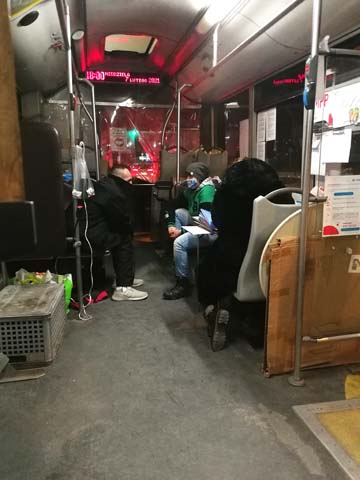 trzy osoby z ładunkami siedzą na krzesełkach w autobusie