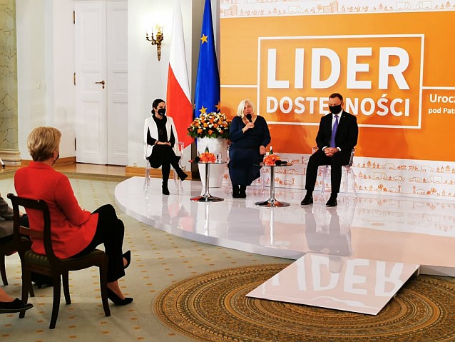 Scena konkursu Lider Dostępności w Pałacu Prezydenckim. Na scenie 3 osoby, w tym prezydent Duda i przemawiająca do mikrofonu Ewa Pawłowska